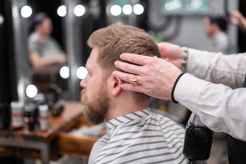 Barbeiro cortando cabelo com tesoura e pente