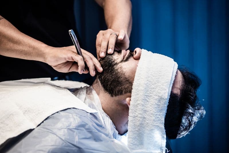 Barbeiro fazendo acabamento e barba em um cliente
