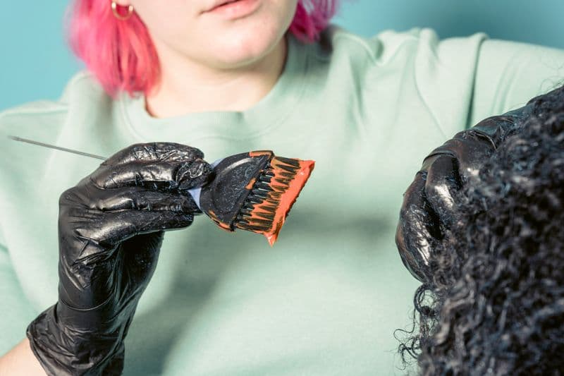 Profissional aplicando coloração no cabelo do cliente