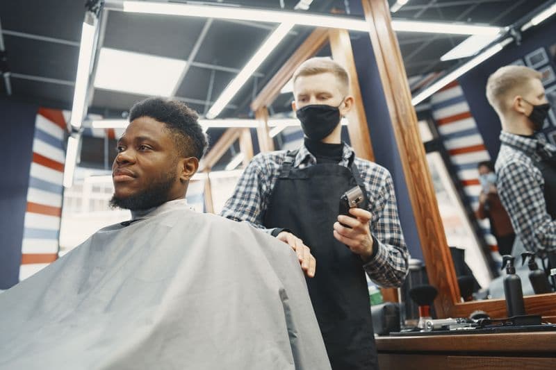 Barbeiro finalizando o degradê da barba de um cliente